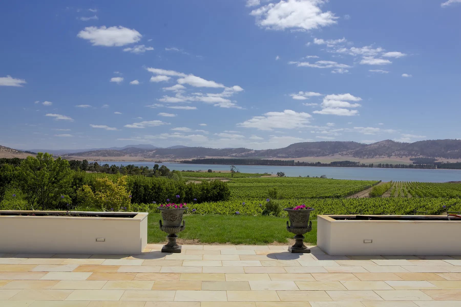A stone garden terrace with planters, looking out over green hills