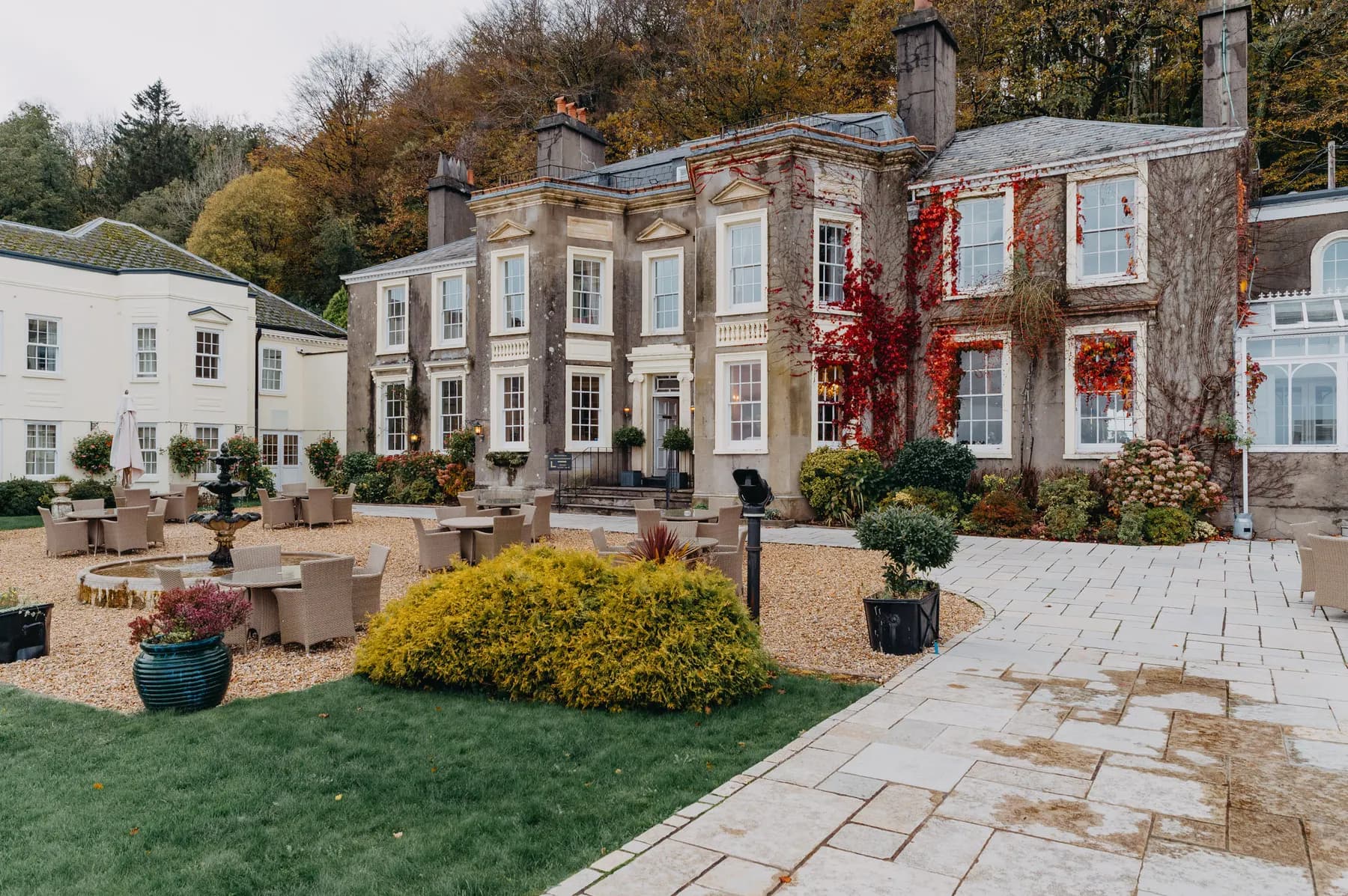 A stone country house with lawns and clipped hedges in front of it